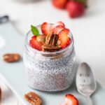 A jar of keto chia pudding with topping suggestions.