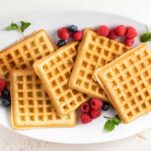 A plate with almond flour waffles surrounded by berries.