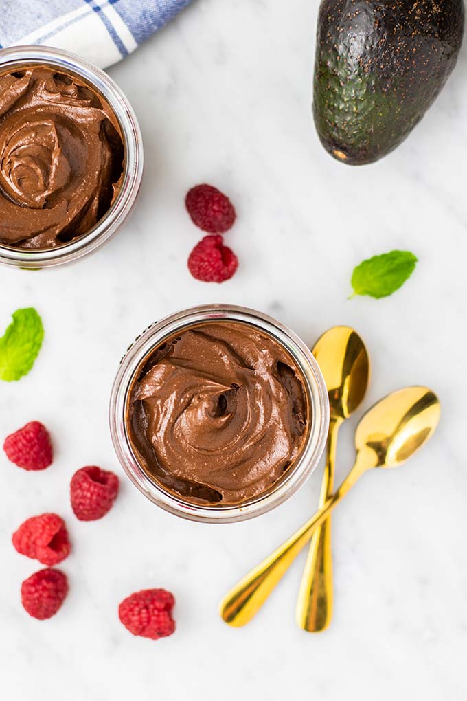A top down view of two jars filled with a thick and creamy avocado pudding.