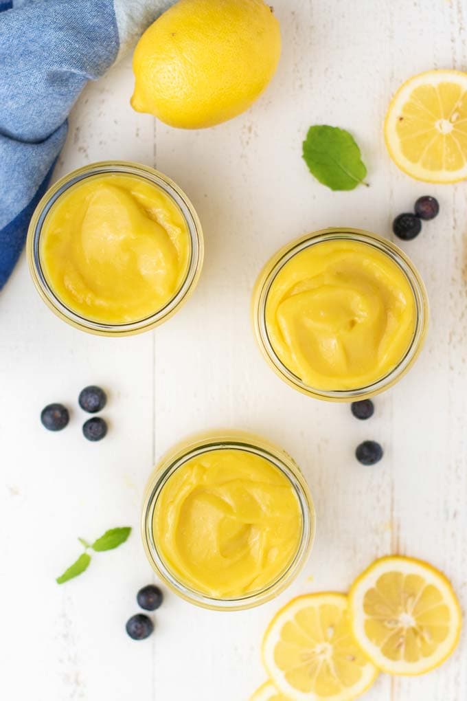 A top down view of 3 jars filled with a vibrant keto lemon curd.