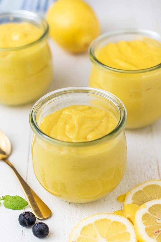 3 jars showing the creamy and thick texture of lemon curd with a gold spoon.