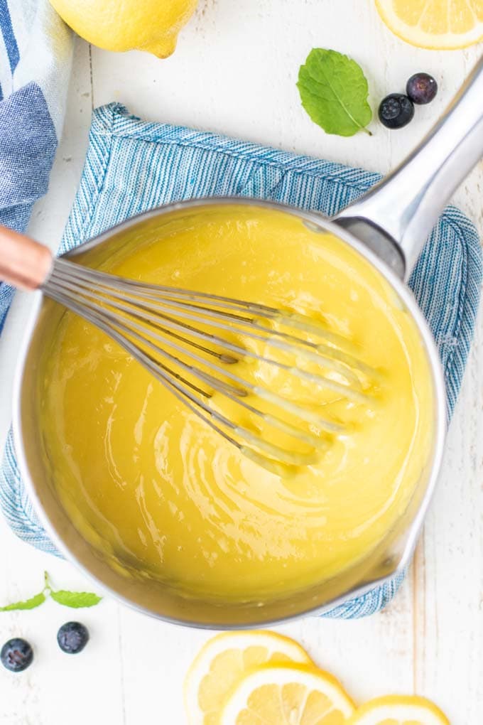 A pan with a whisk showing the texture of lemon curd when it's finished cooking.