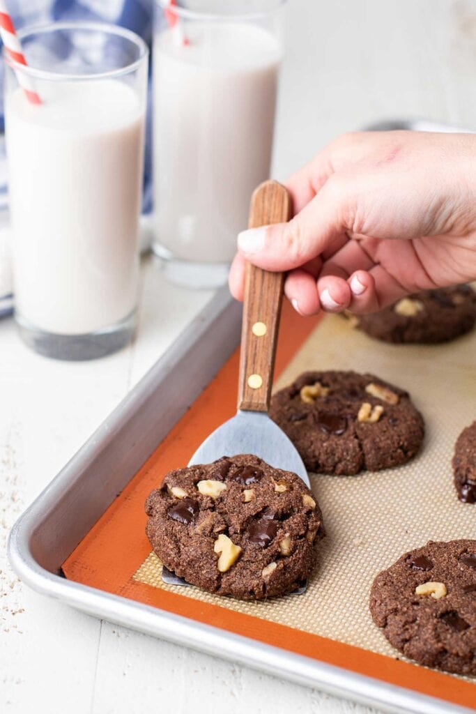 A spatula picking up a cookie off a baking tray.