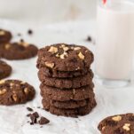 A stack of keto double chocolate chunk cookies next to a glass of milk.