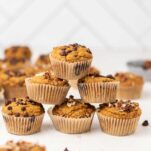 A pyramid of keto pumpkin muffins topped with pecans and chocolate chips.