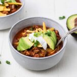 A side angle view of two bowls of chili with avocado.