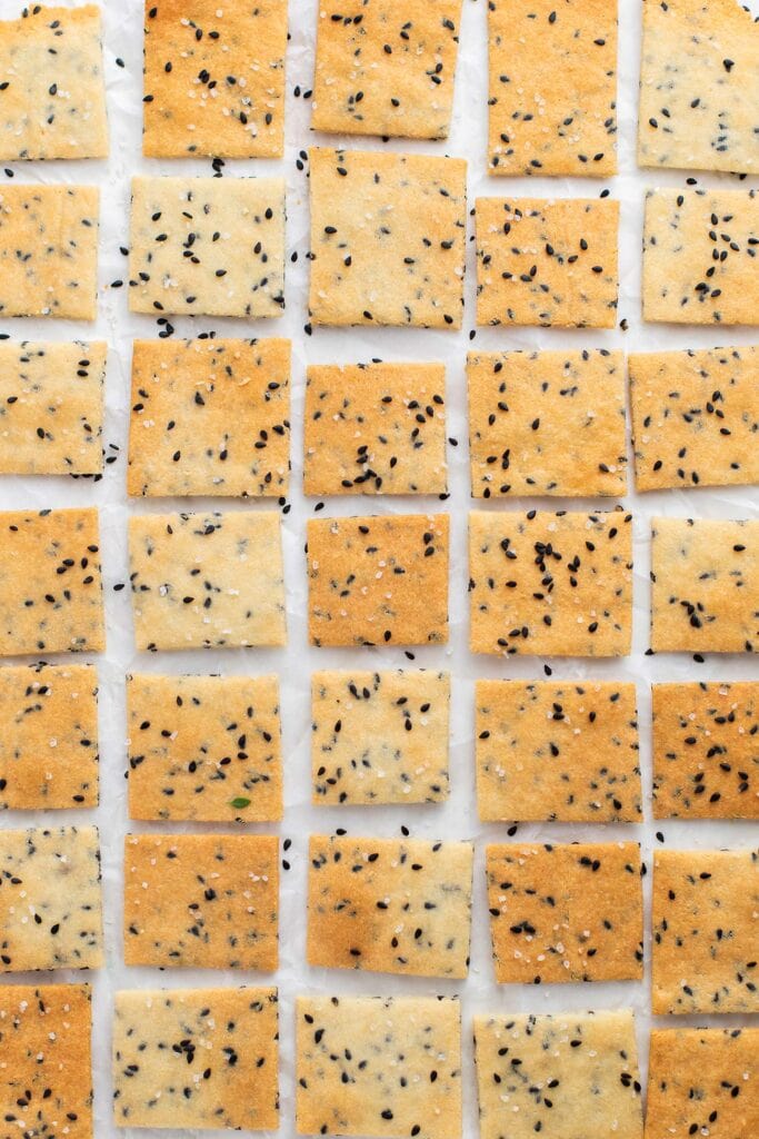 Almond flour crackers shown sprinkled with black sesame seeds.
