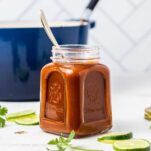 A jar of enchilada sauce in front of a blue cast iron pot.