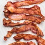 A plate with lots of crispy bacon shown cooked in an air fryer.