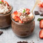 A jar of keto chocolate chia seed pudding topped with whipped cream and strawberries.