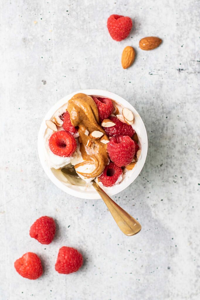 A Greek yogurt cup with raspberries and almond butter.