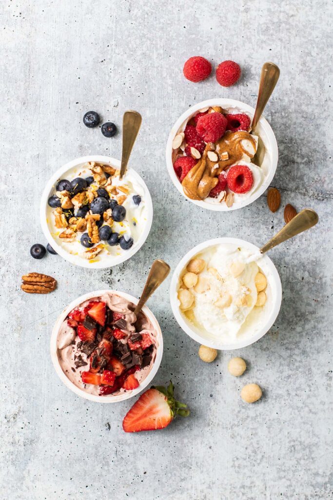 4 keto Greek yogurt recipes with berries, nuts, coconut, and chocolate added to them.