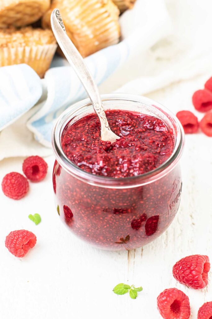 A glass jar filled with a sugar free raspberry jam.