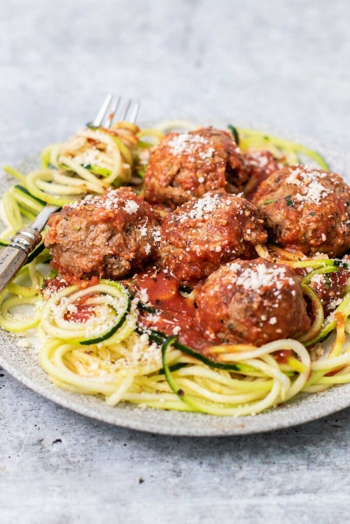 A plate of zoodles topped with zucchini meatballs and marinara sauce.