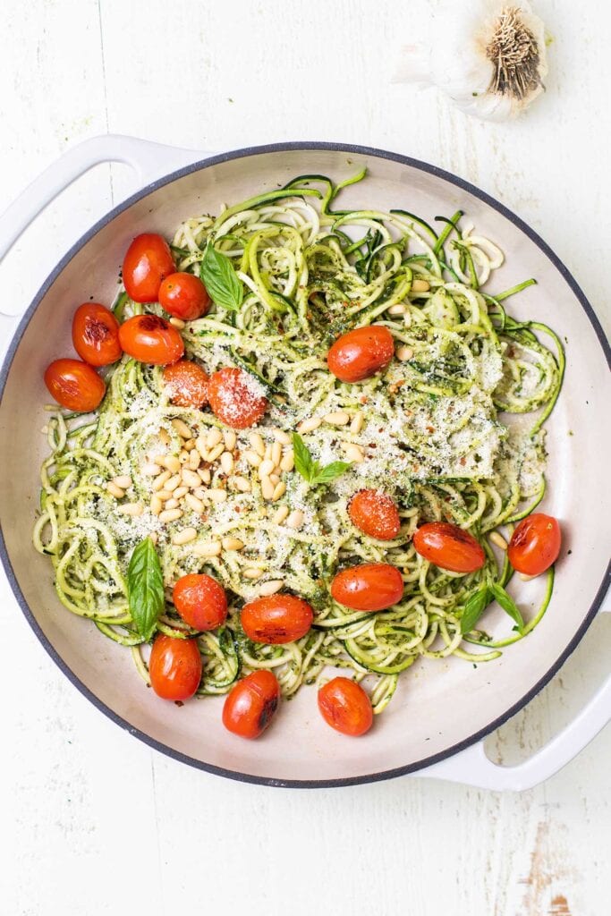 Pesto zoodles shown with flavorful garnish options.