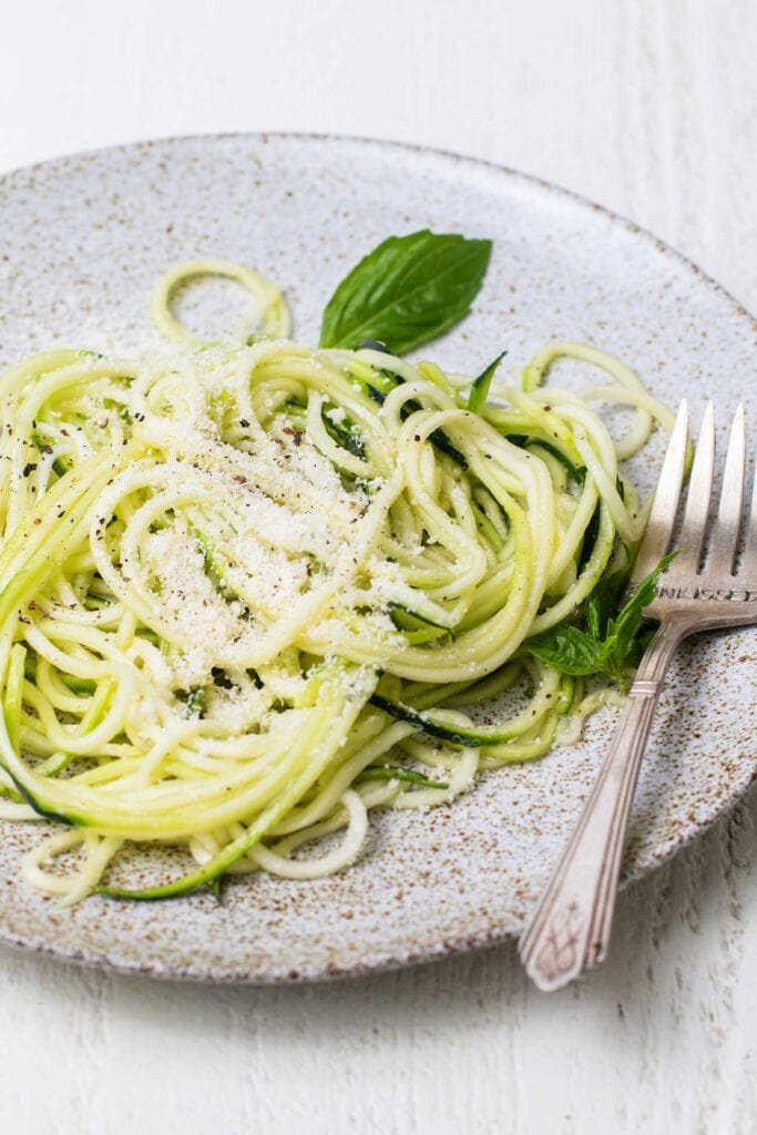 A bed of zucchini noodles shown with a simple parmesan and butter mixture.