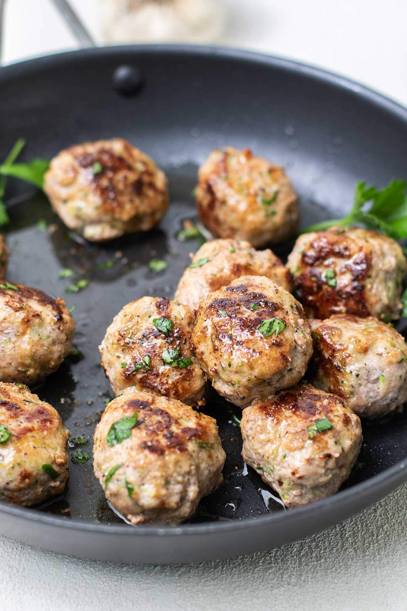 A stack of low carb meatballs shown in a skillet.