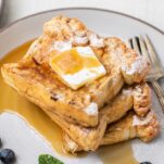 A stack of French toast with butter and maple syrup.