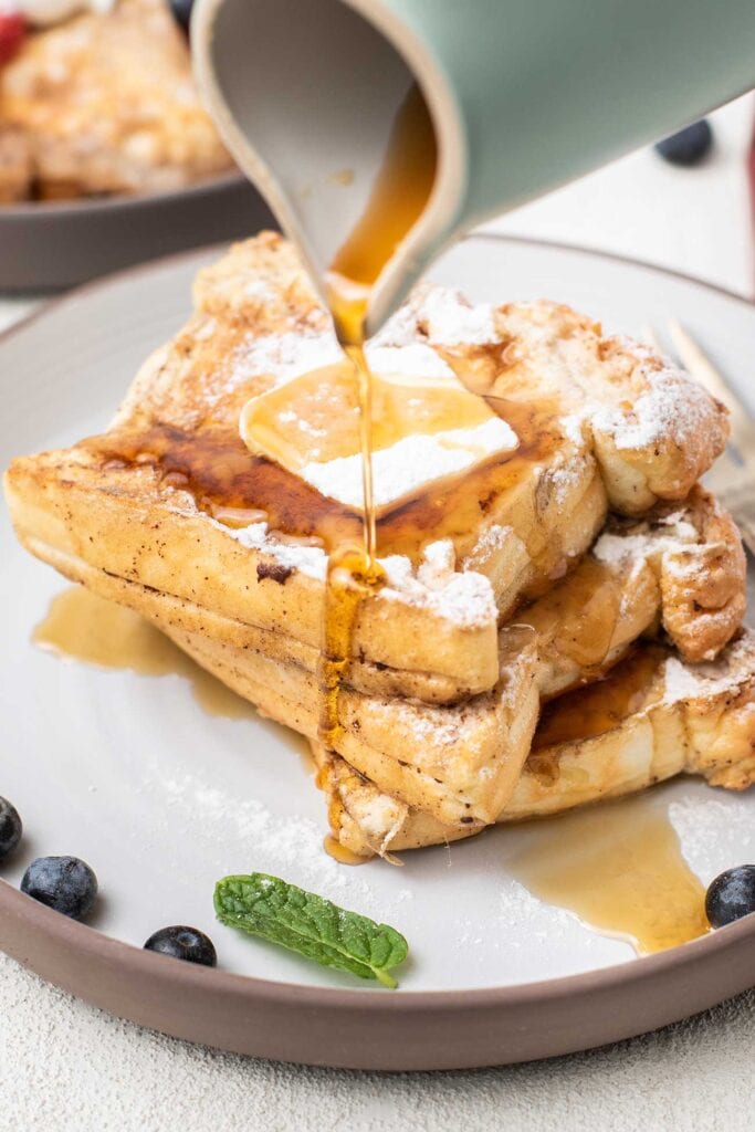 A plate of keto french toast shown being drizzled with maple syrup.