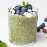 A close up look at a glass filled with matcha chia pudding and blueberries.