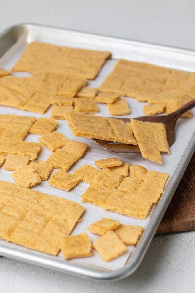 The crackers on a baking tray being flipped over to brown and crisp up evenly.