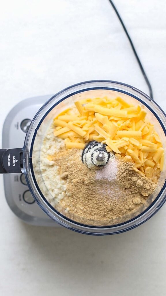a food processor bowl with cheddar cheese, almond flour and flax meal.