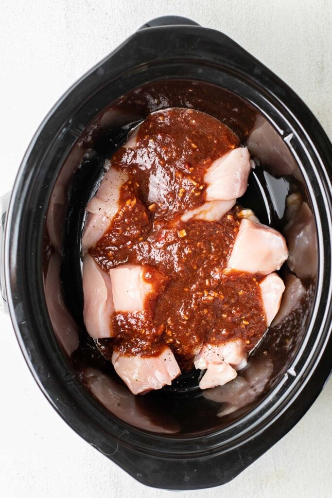 The chicken and Asian sauce added to a crockpot.