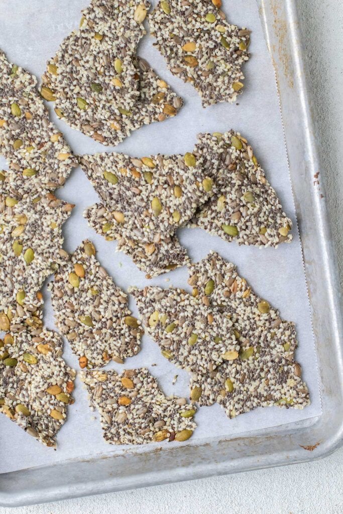 A baking pan shown with chia seed crackers broken into pieces.