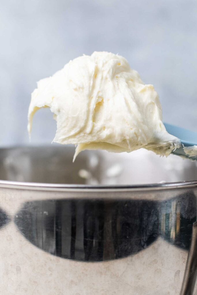 A fluffy vanilla Keto Cream Cheese frosting on a blue spatula.