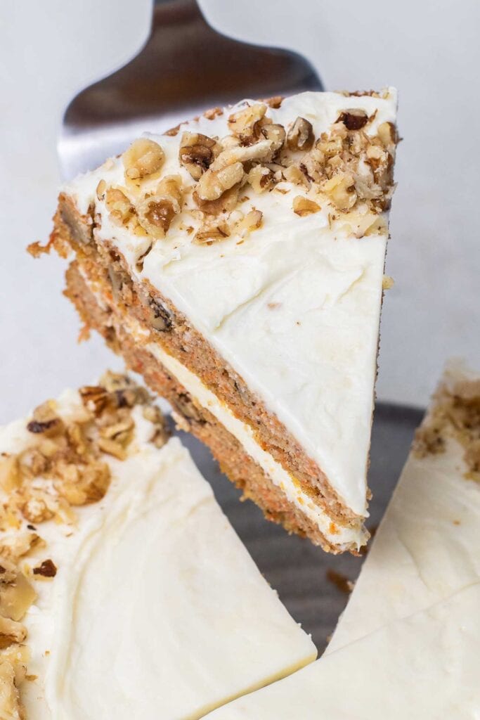 A slice of keto carrot cake being lifted from the cake pan.