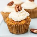 A carrot cake cupcake garnished with a pecan.