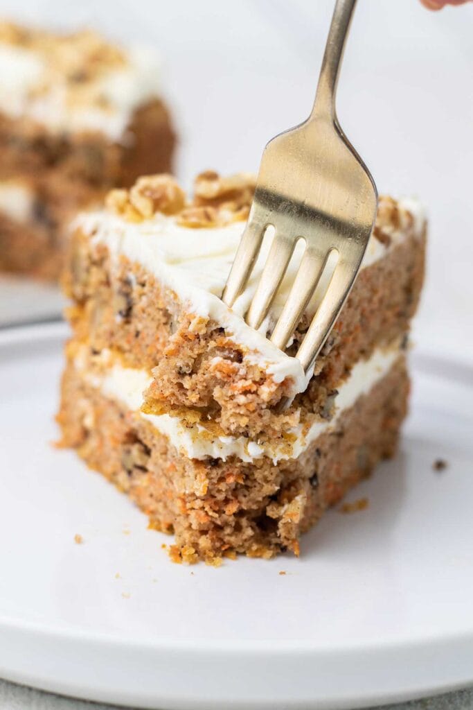 A fork taking a bite out of a slice of keto carrot cake.