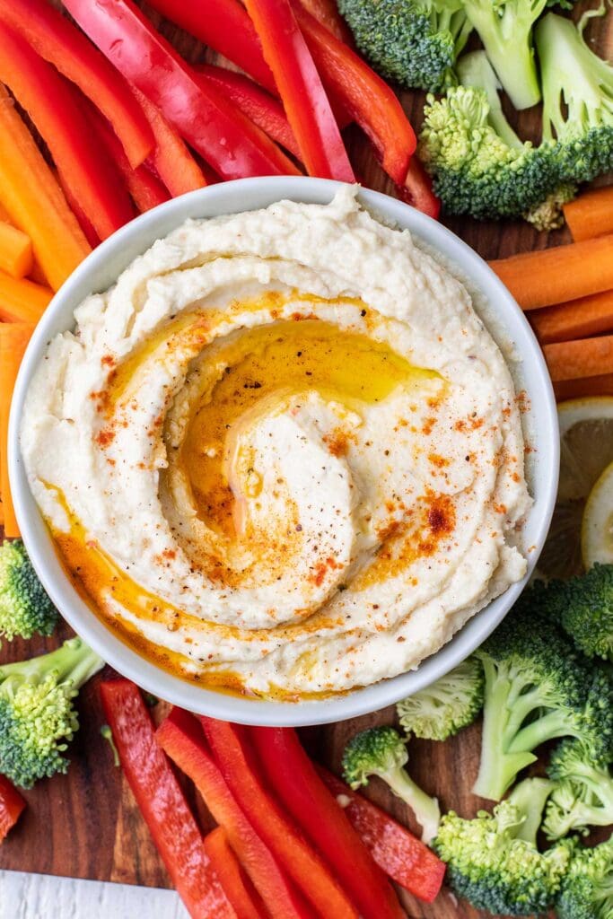 A bowl of cauliflower hummus drizzled with olive oil and garnished with paprika.
