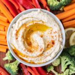 A bowl of roasted cauliflower hummus surrounded by low carb dippers.