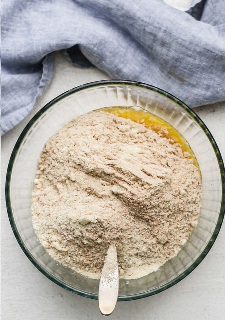 The dry ingredients shown added into the bowl with the wet ingredients to make an almond flour cake batter.