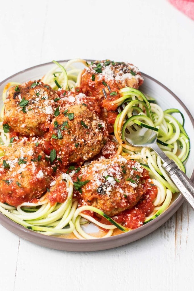Keto Chicken Meatballs with marinara sauce served over zoodles.