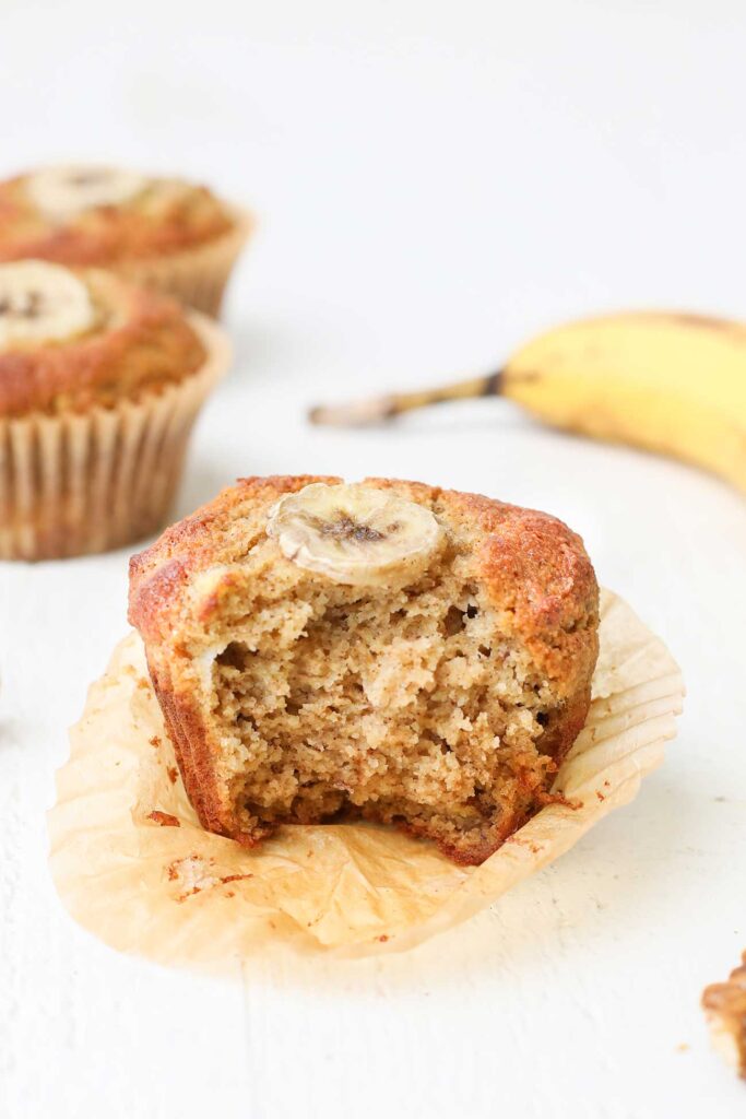 A fluffy banana muffin shown with a bite taken out.