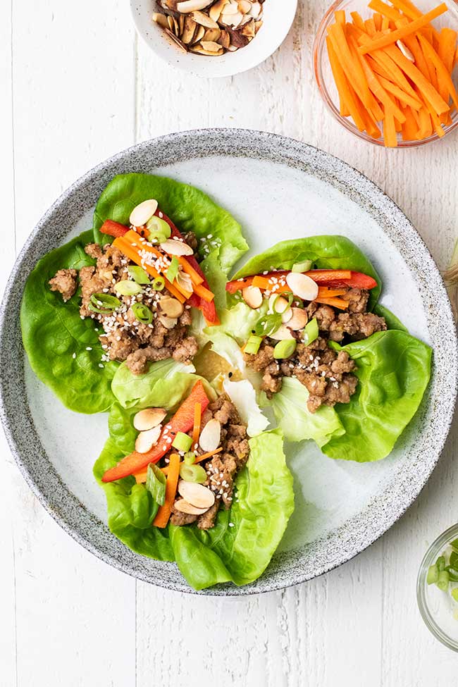 Pork lettuce wraps topped with shredded veggies and almonds.