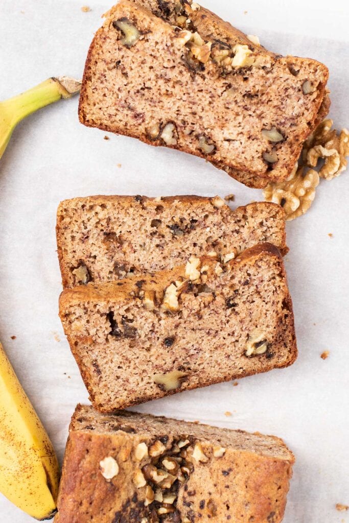 A loaf of keto banana bread with walnuts shown cut into slices.