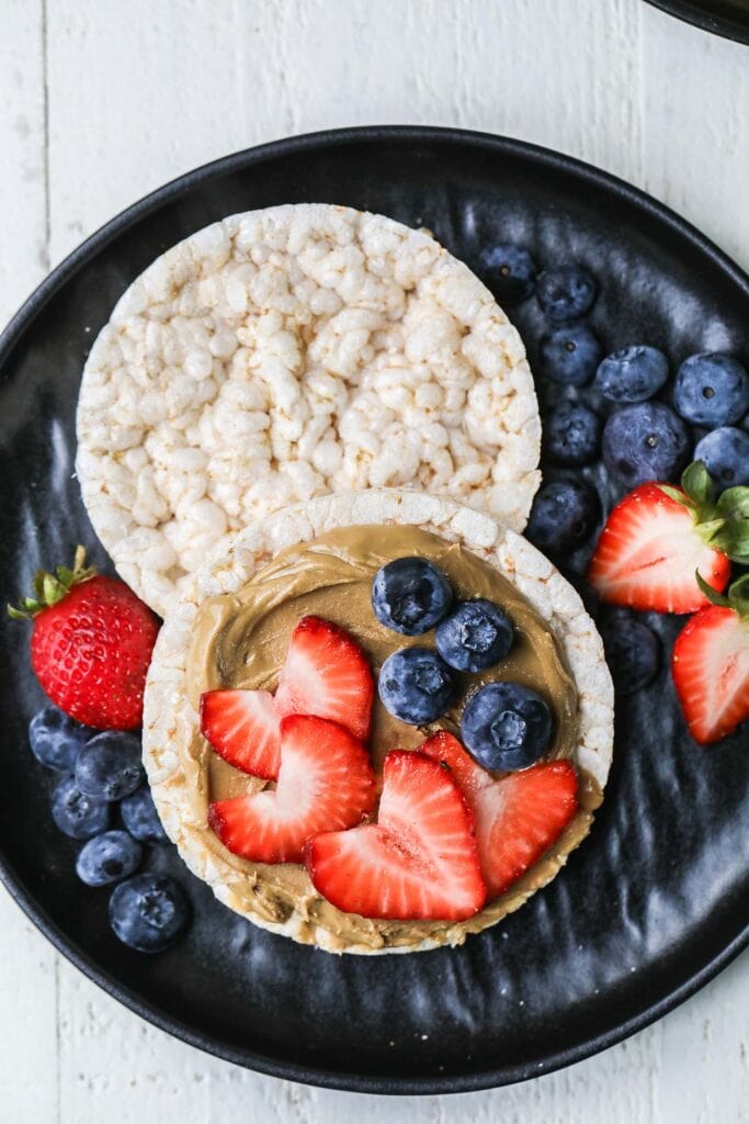 A plate with rice cakes shown topped with nut butter and berries.