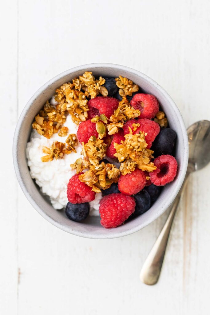 A bowl of cottage cheese topped with blueberries, raspberries, and keto granola.