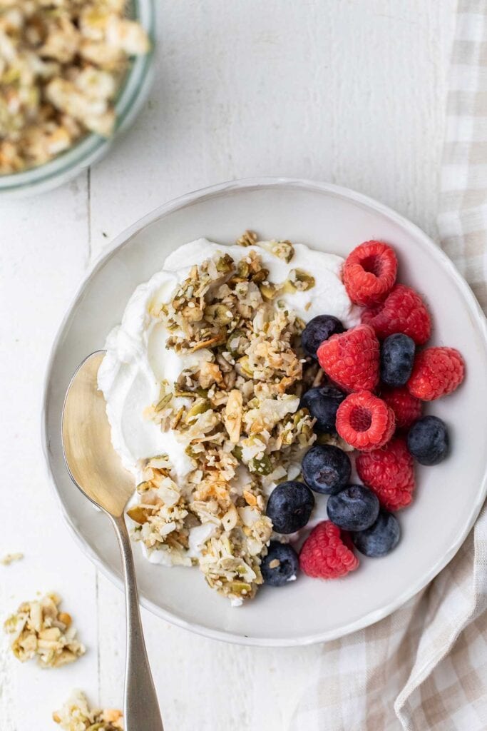 A bowl of yogurt topped with berries and grain free granola.