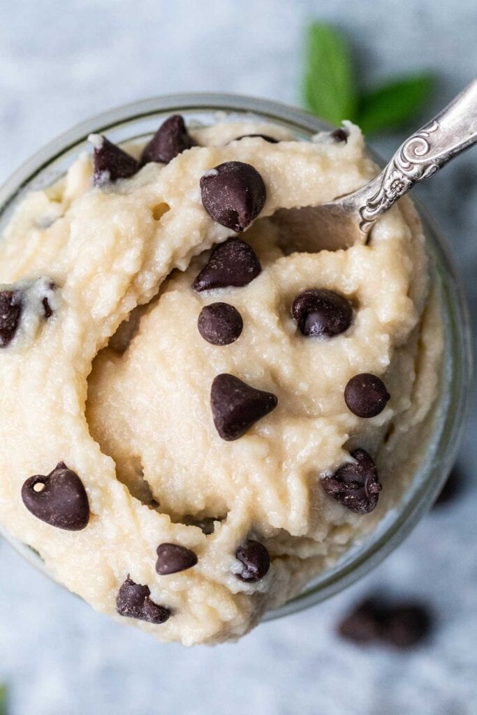 A close up look at a spoon scooping up some cookie dough with protein powder.