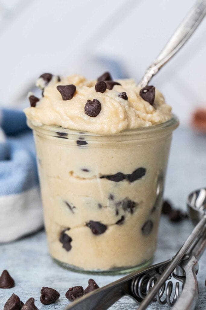A glass jar filled with an edible high protein cookie dough.