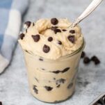A close up look at a jar of high protein cookie dough with lots of chocolate chips on top.