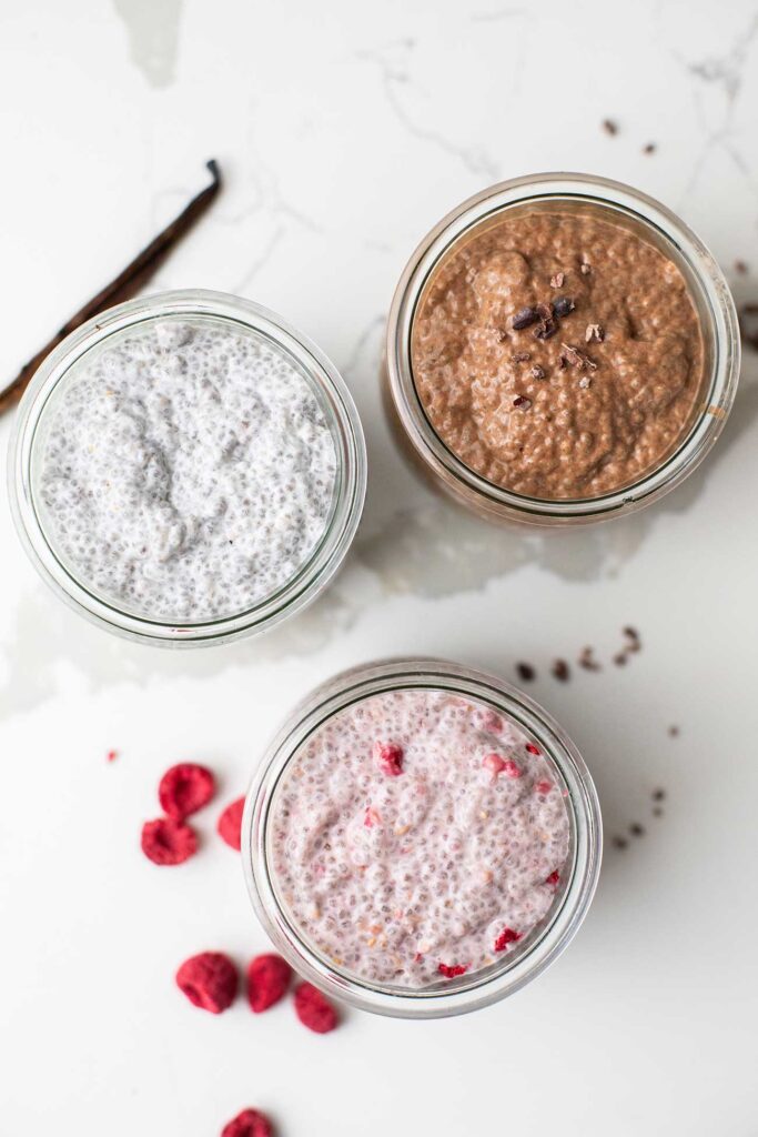 Jars of protein chia pudding shown in vanilla, raspberry, and chocolate flavors.
